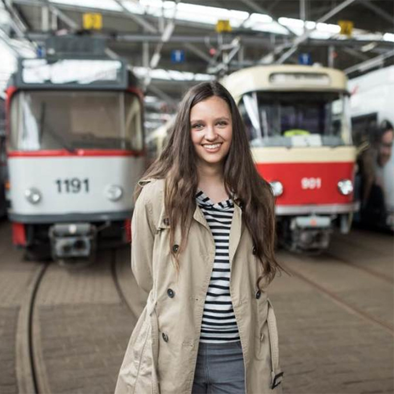 Junge Frau vor zwei Straßenbahnen.