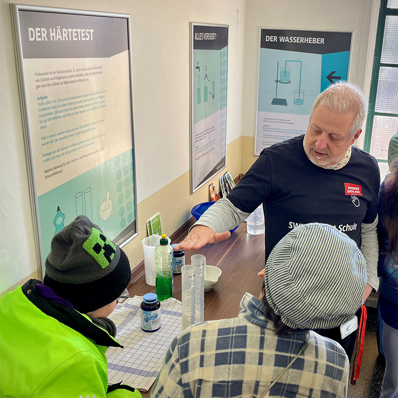 Mitarbeiter erklärt Kindern eine Station der Wasserwerkstatt.