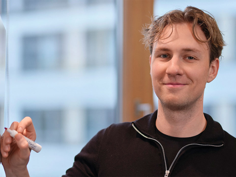 Mitarbeiter schreibt mit Stift auf Whiteboard.
